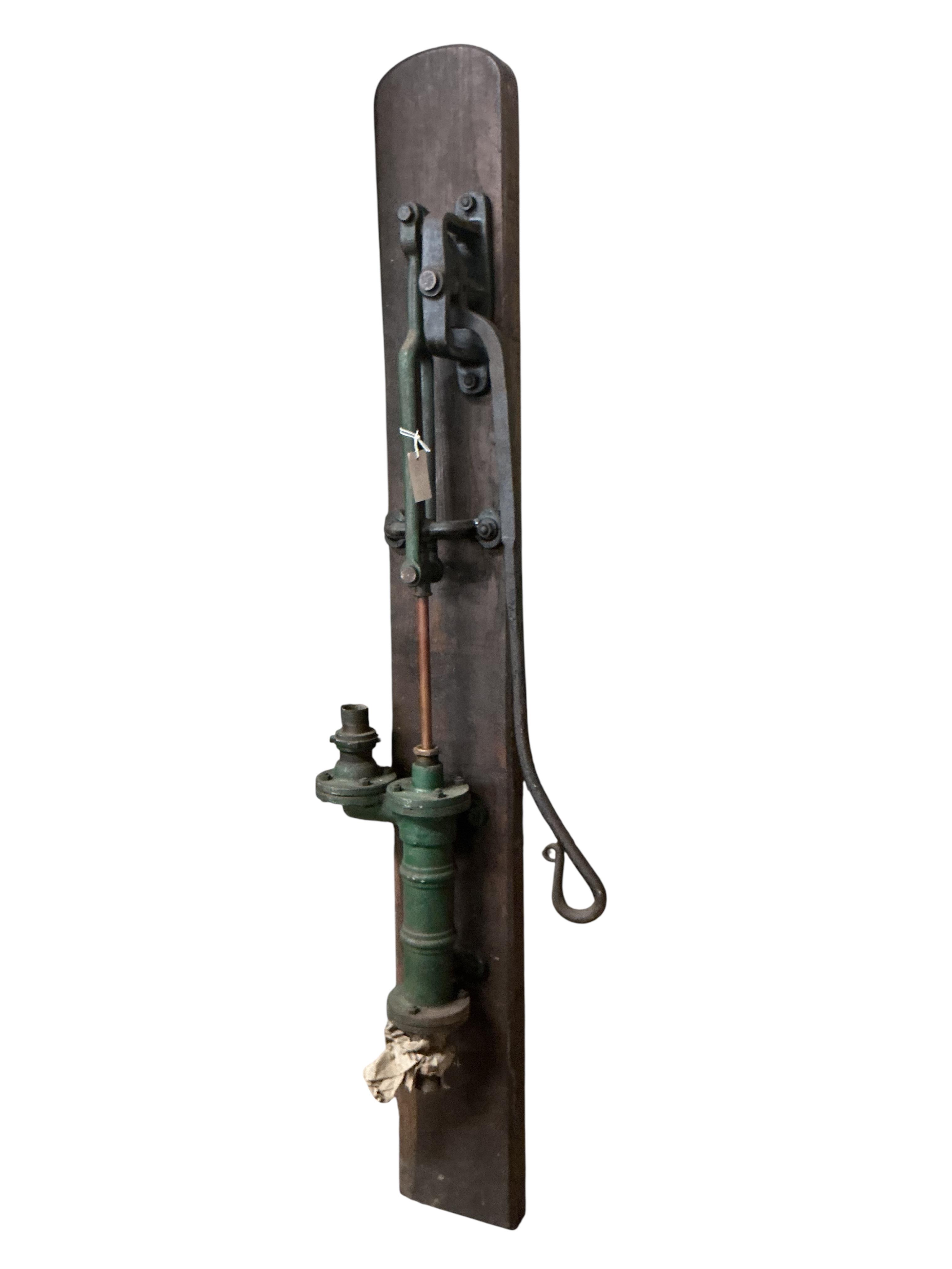 A Victorian cast iron water pump, mounted on a board, height including back board 80cm